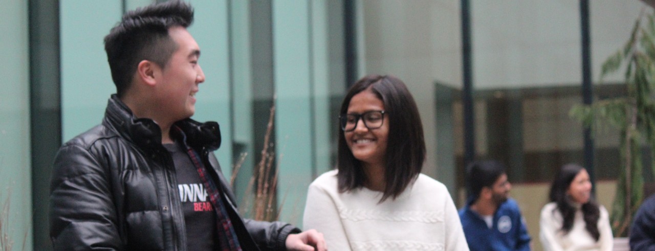 Two international students talk to each other in the Lindner College of Business courtyard.