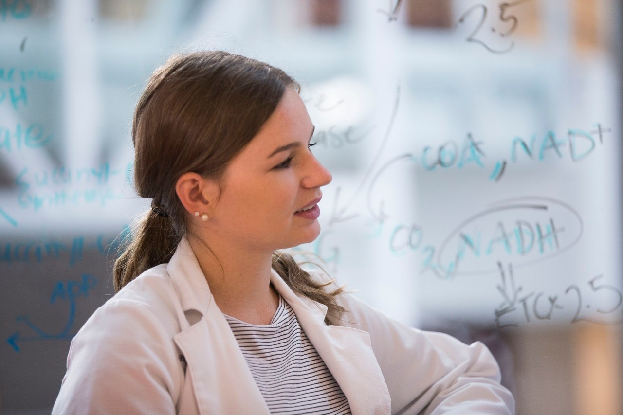 Profile of a young woman in a lab coat.