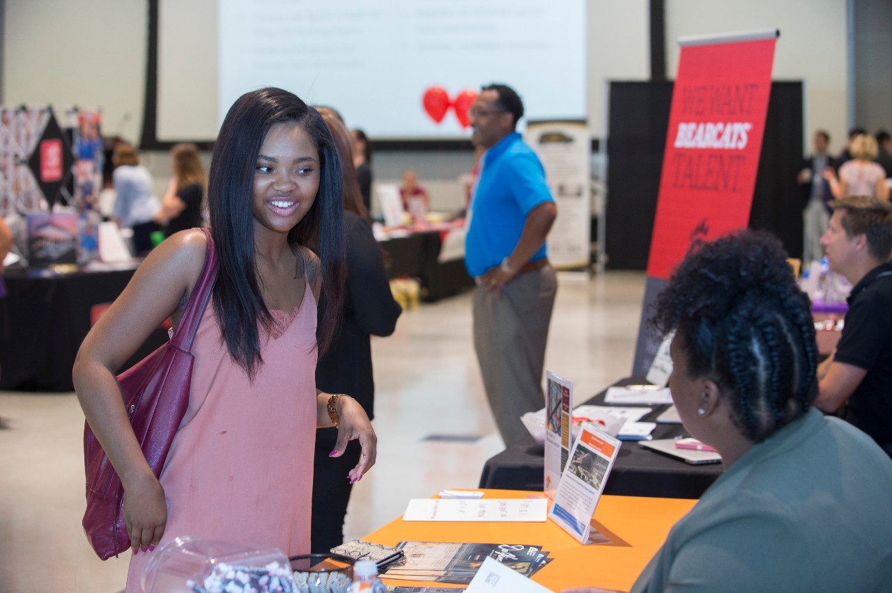 Young woman talking to a recruiter at a fair.