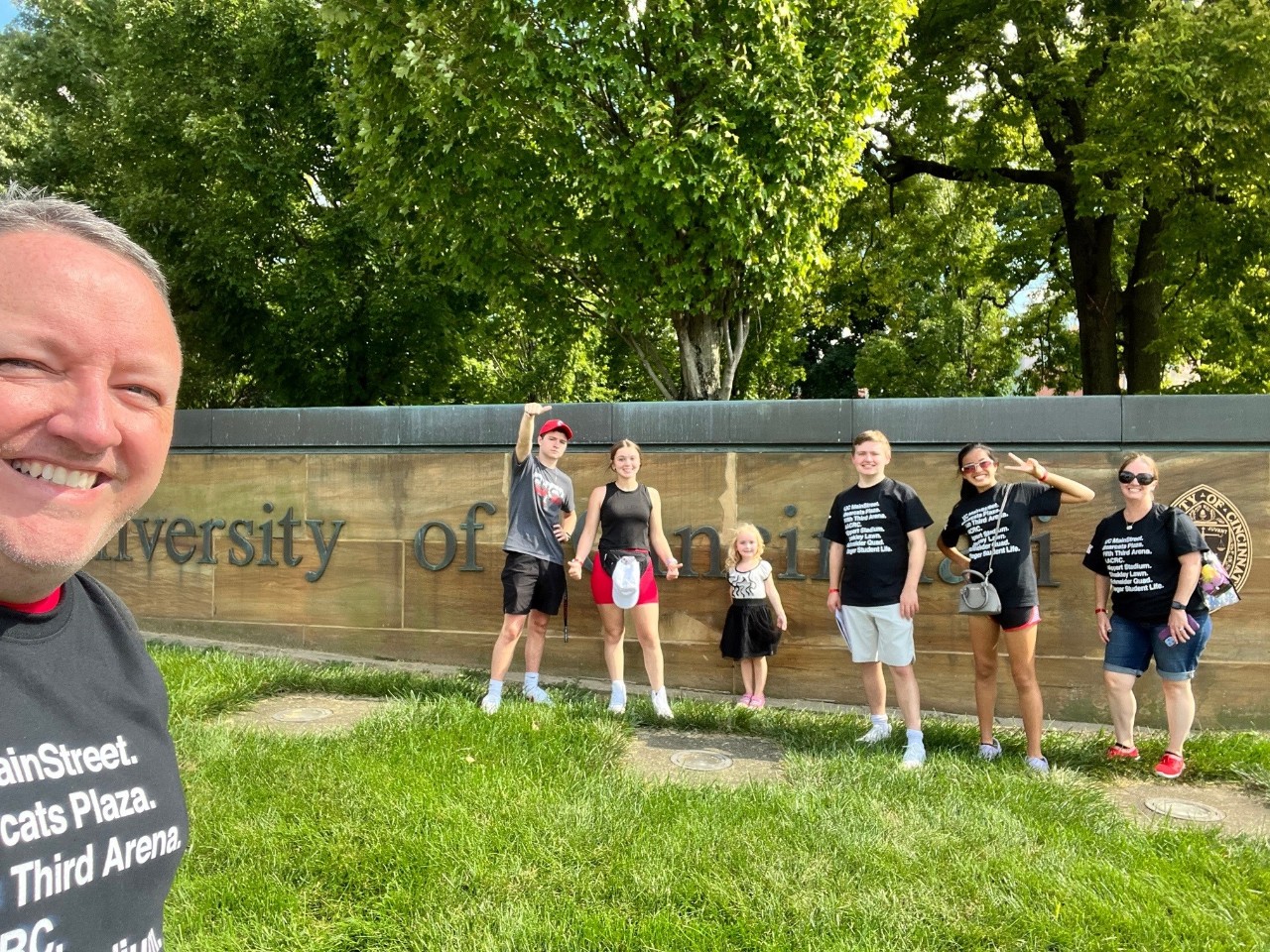 Family posing in front of University of Cincinnati sign at Family Weekend