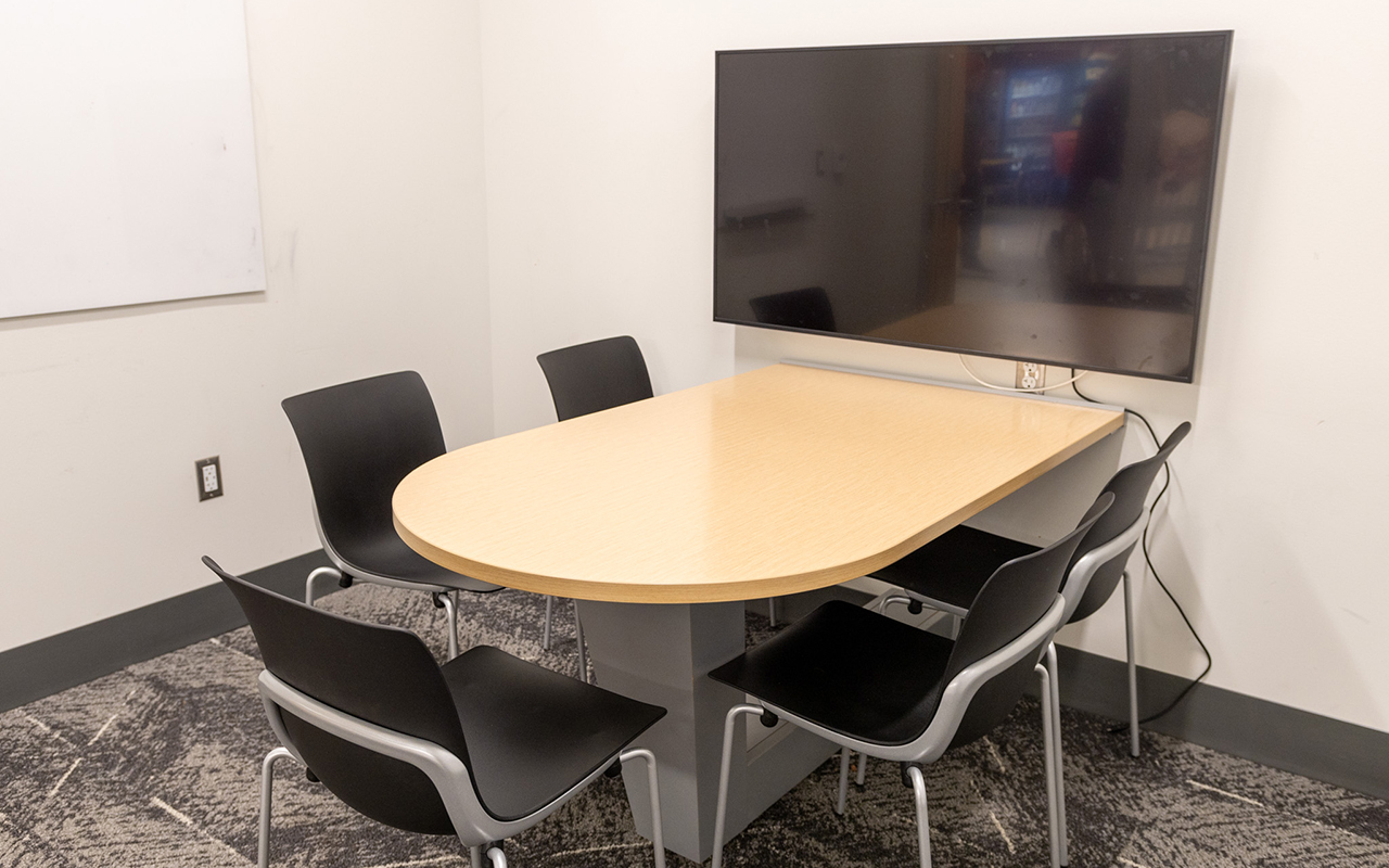 Study room with white board, digital monitor and table with five chairs