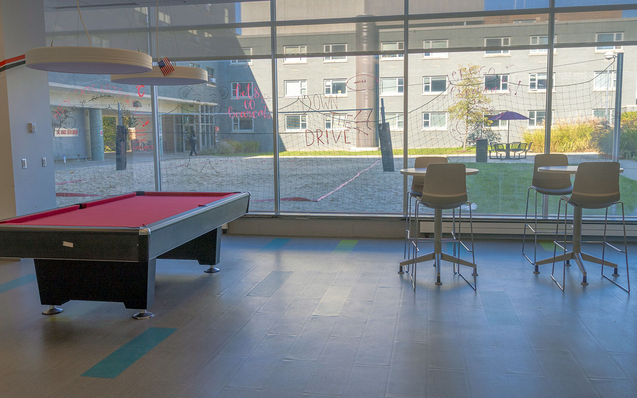 Lounge area with pool table, high-top tables and chairs, and windows with a view of the courtyard