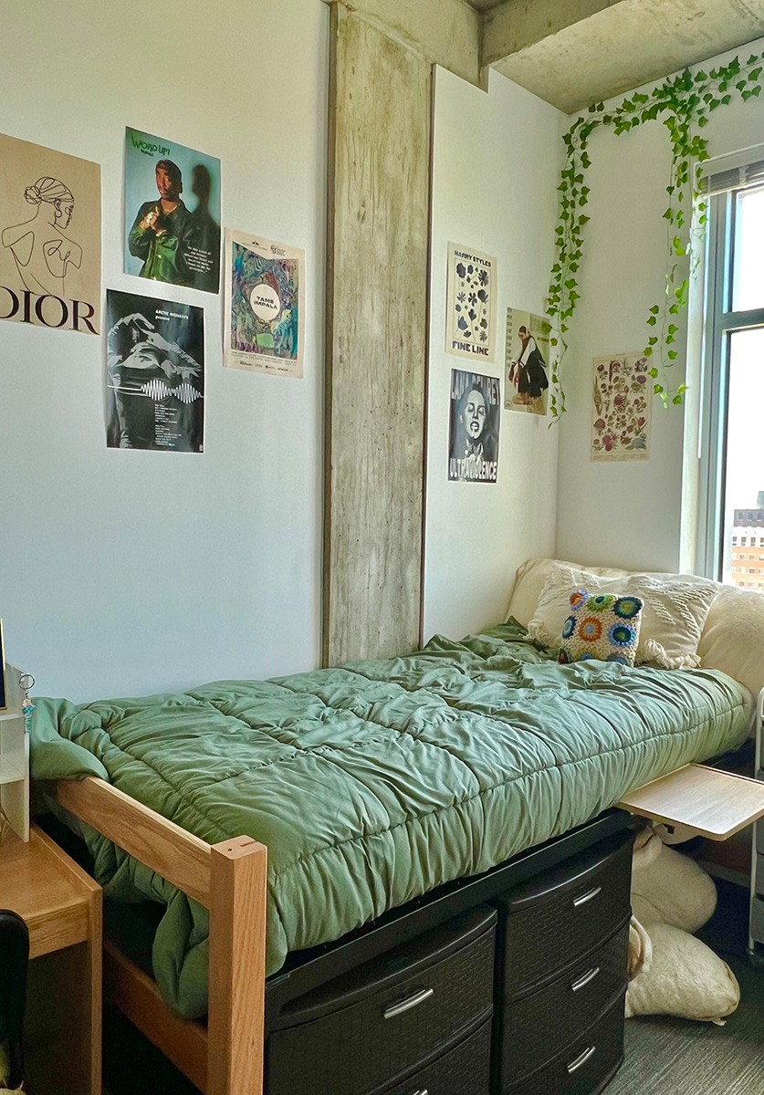 Bed with green cover, vines and pictures on wall