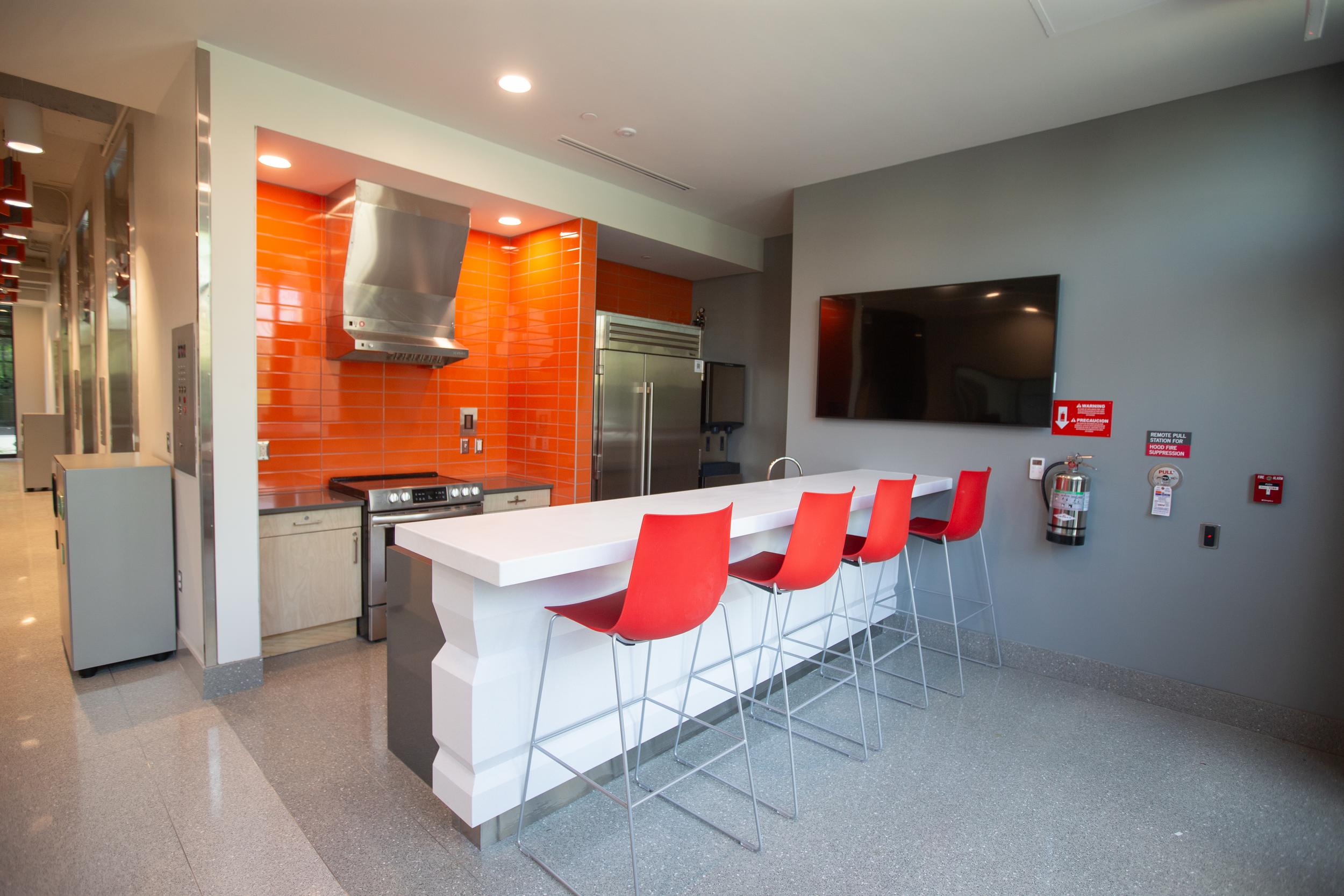 Shared kitchen with refrigerator, cooktop and high counters with chairs