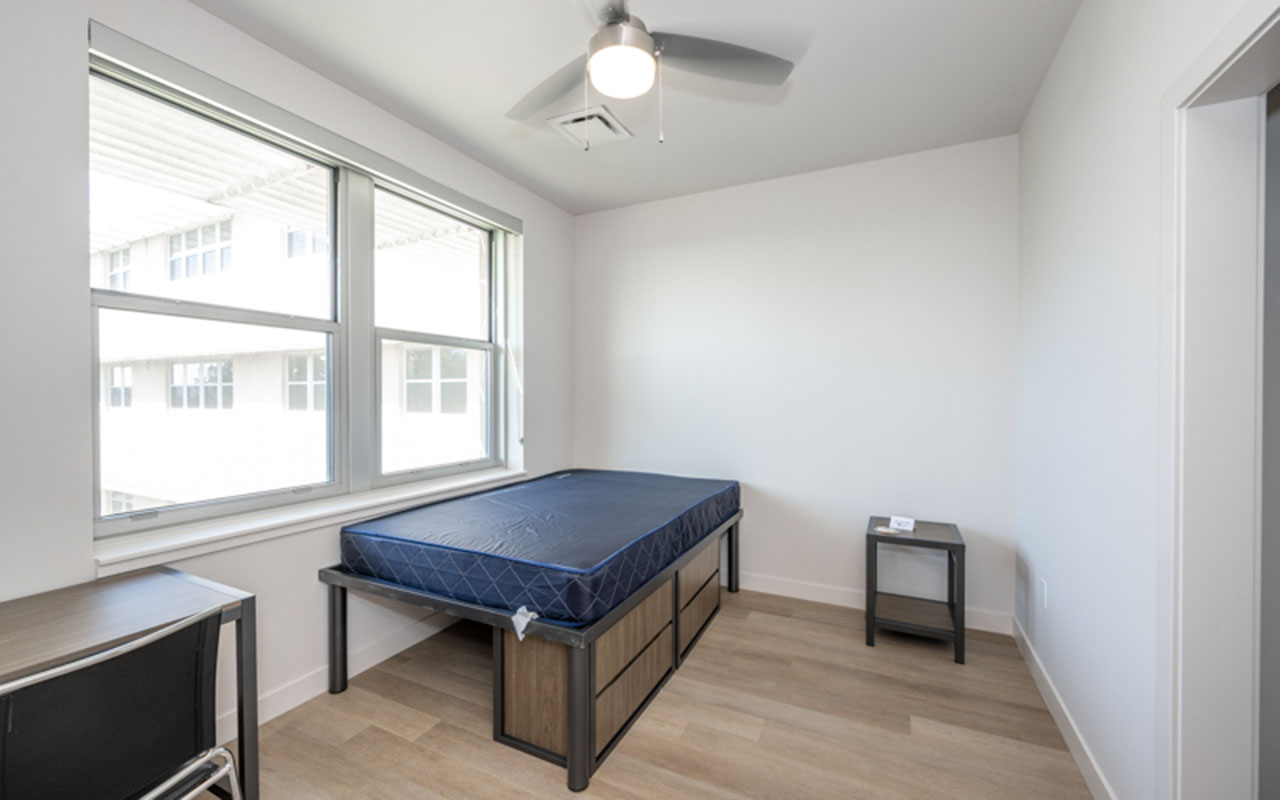 Bedroom with bed, underbed storage, desk and nightstand