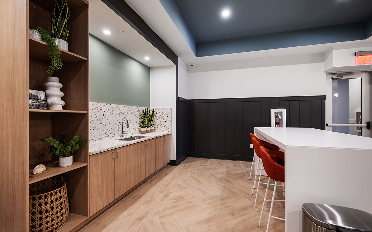 View of  tall work table, shelving with decorative home goods and sink with counter