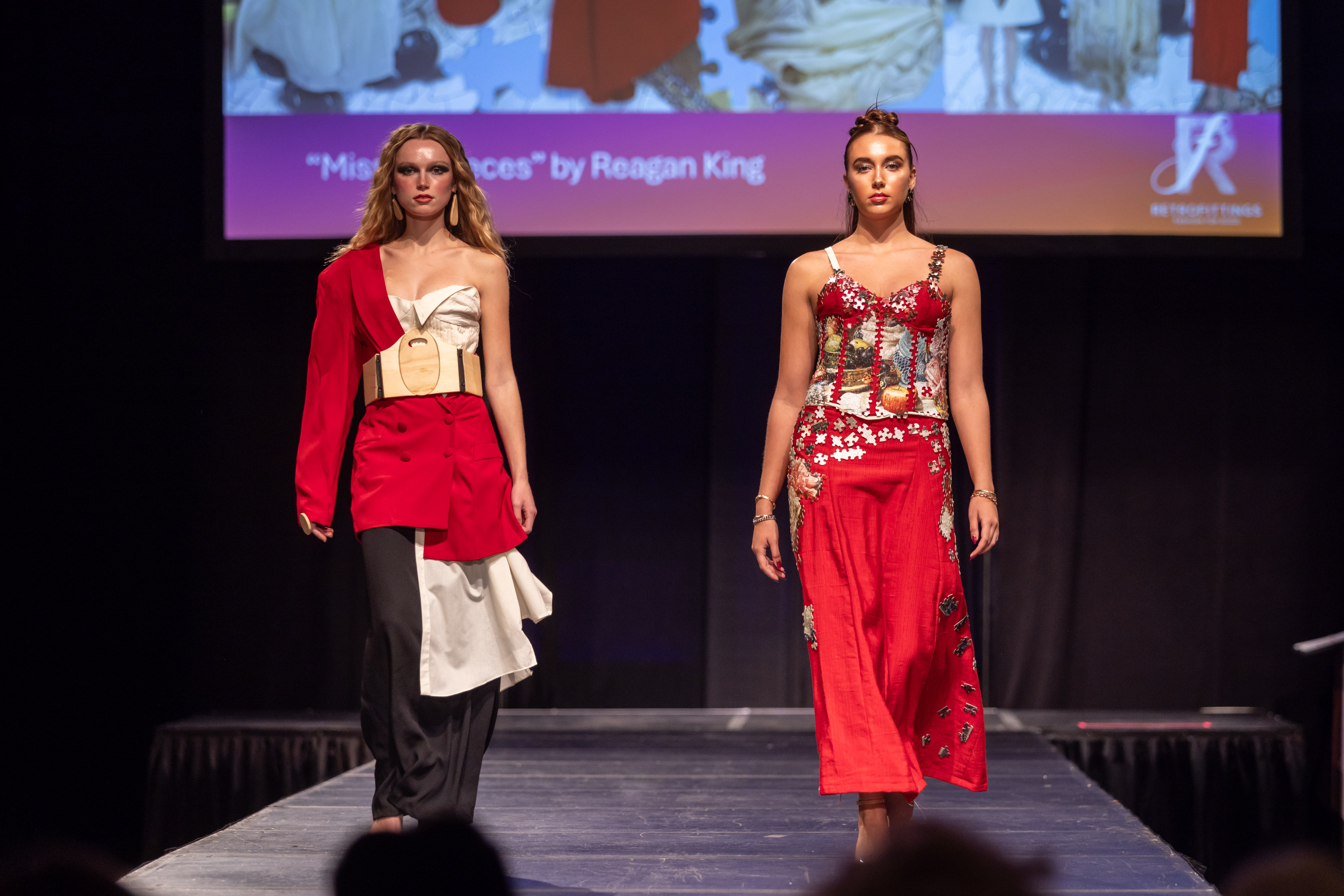 Two models on the runway wearing red dresses crafted from thrifted items