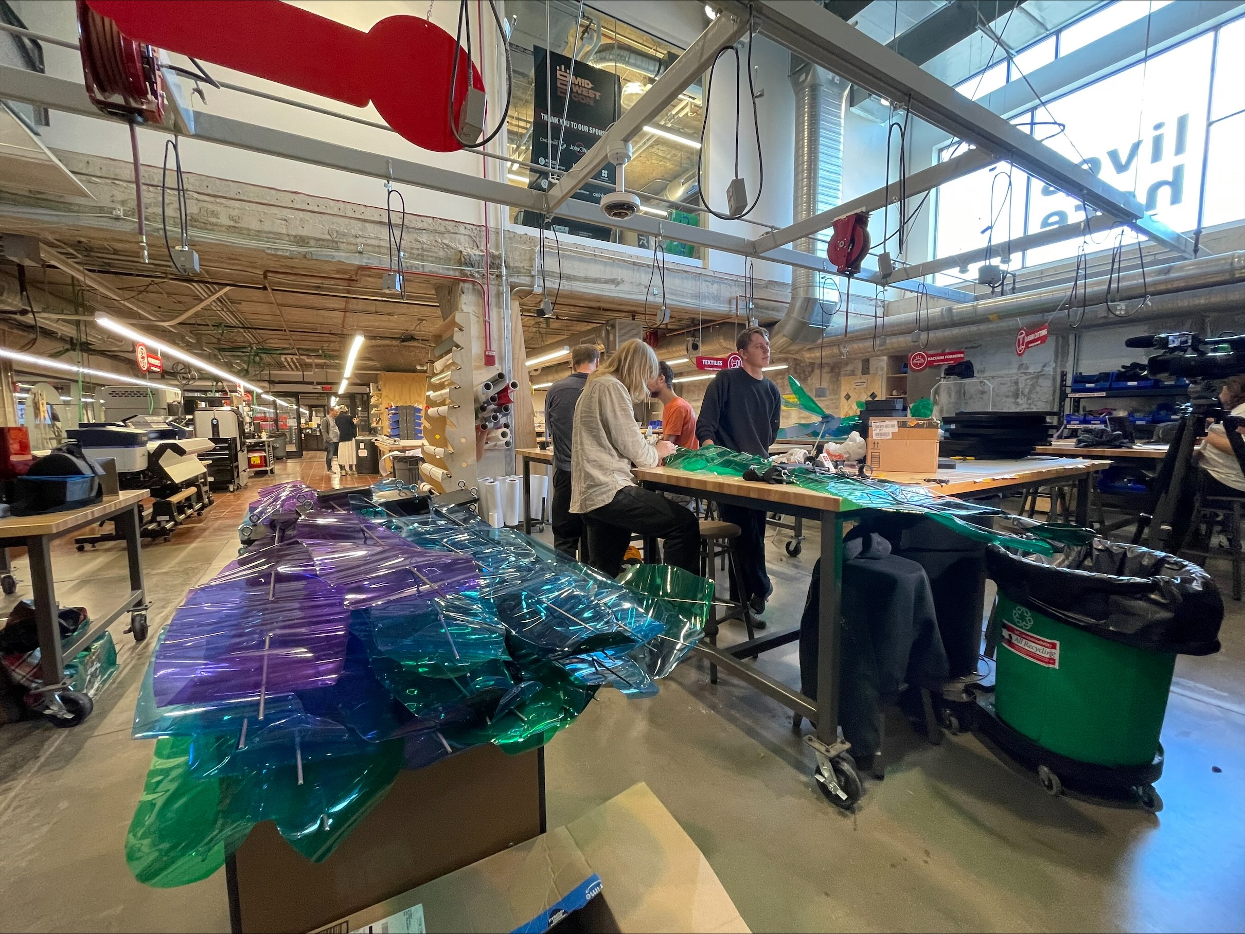 People work in the Makerspace with dragonfly wings in the foreground.