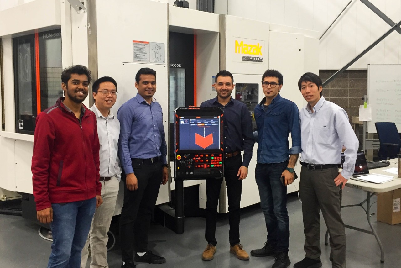 Six UC research team members pose with Mazak machine in a lab.