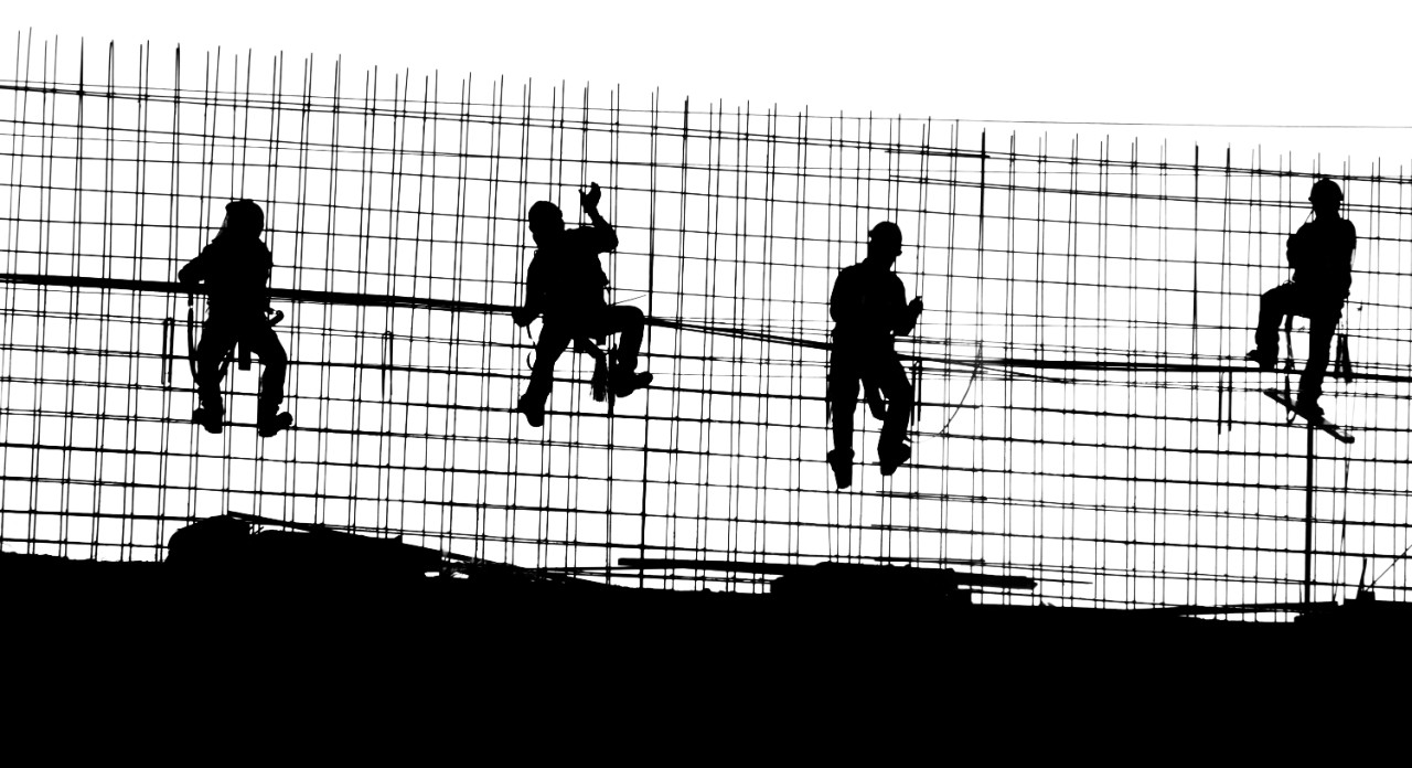 The silhouettes of construction workers on a job site.