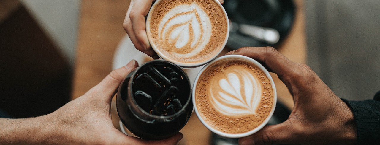 Three people toasting coffee cups, bird's eye view shot.
