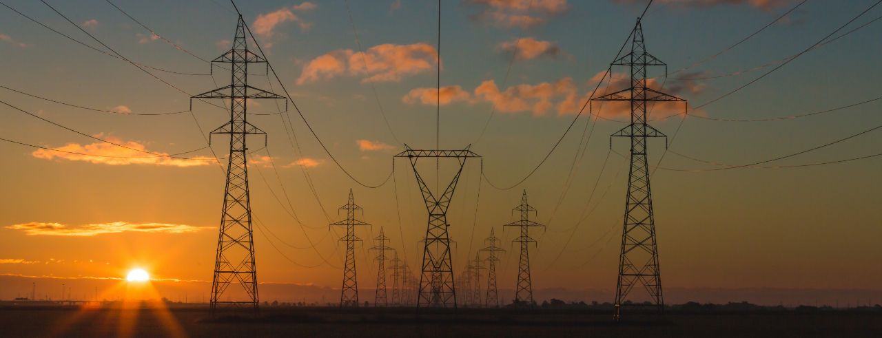 a series of power line pylons with a colorful sunset in the background