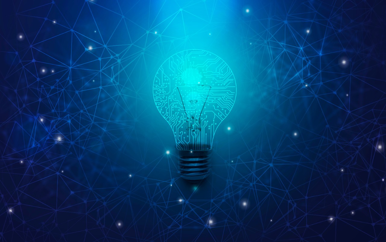 Abstract light bulb with circuit board lines inside over blue polygonal background, panorama