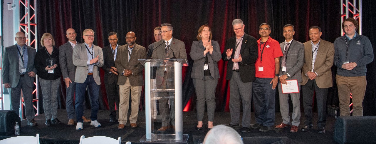 Representatives from the Ohio Cyber Range Institute’s Regional Programming Centers stand on a stage.