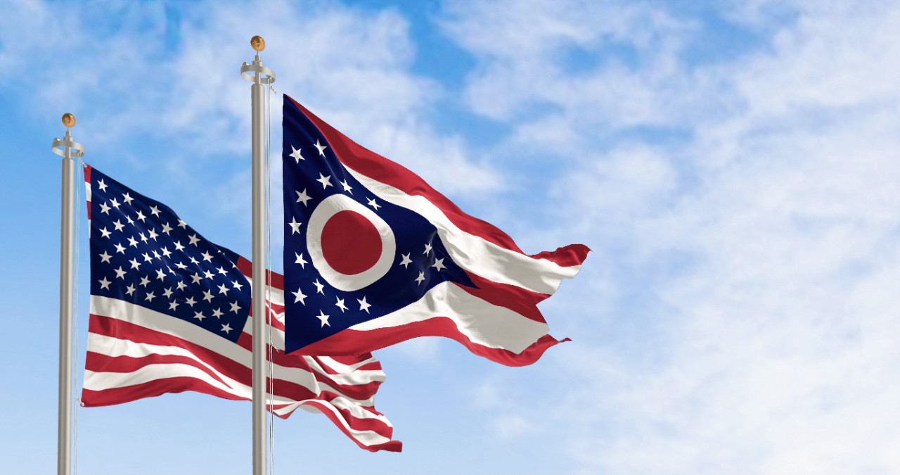 American and Ohio flags waving against a blue sky
