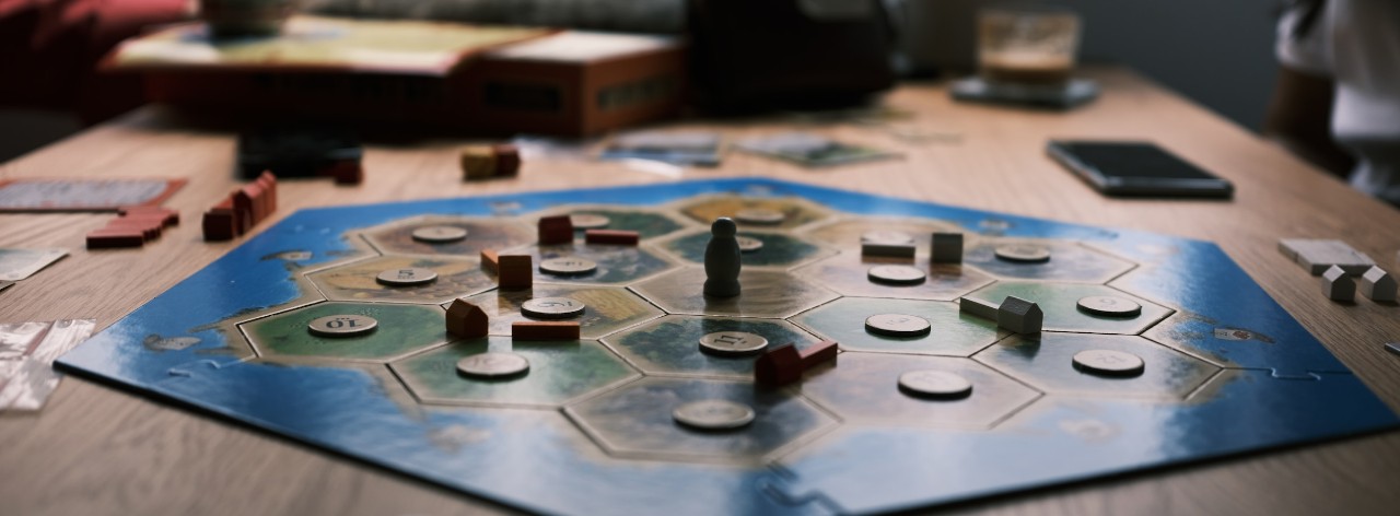 the board game Catan on a table with game pieces and tokens