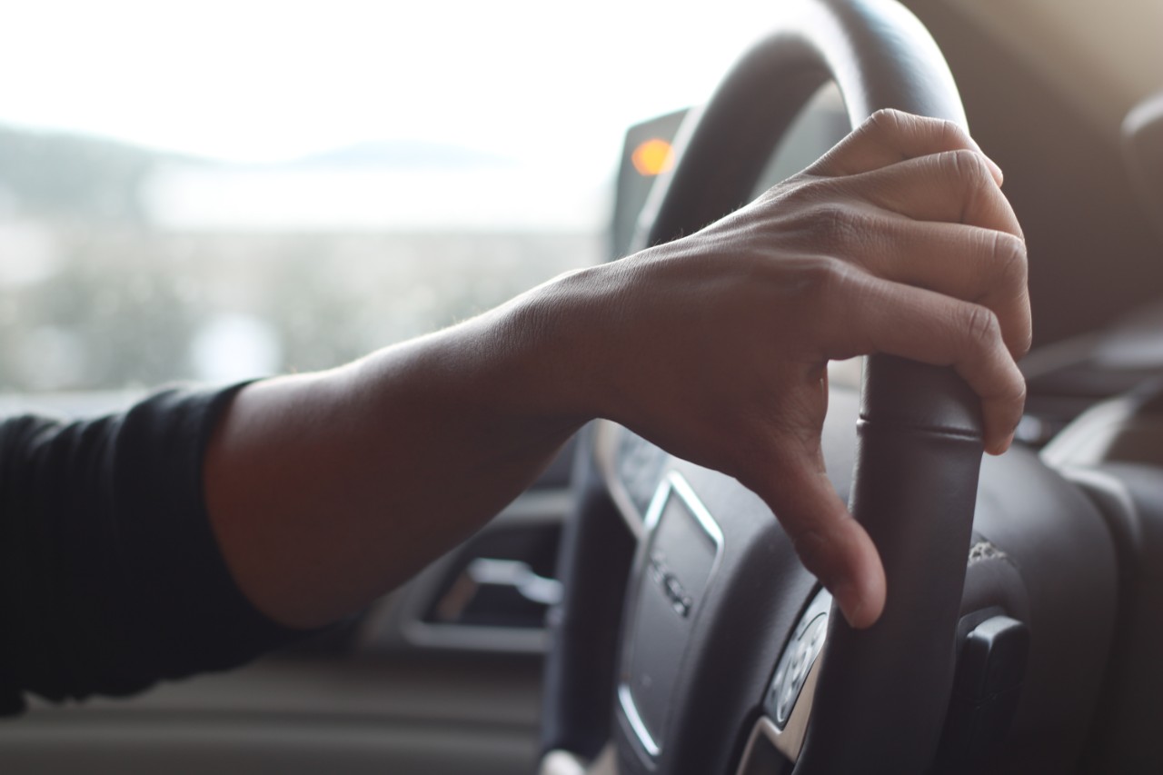 A person puts their hand on the steering wheel of a car