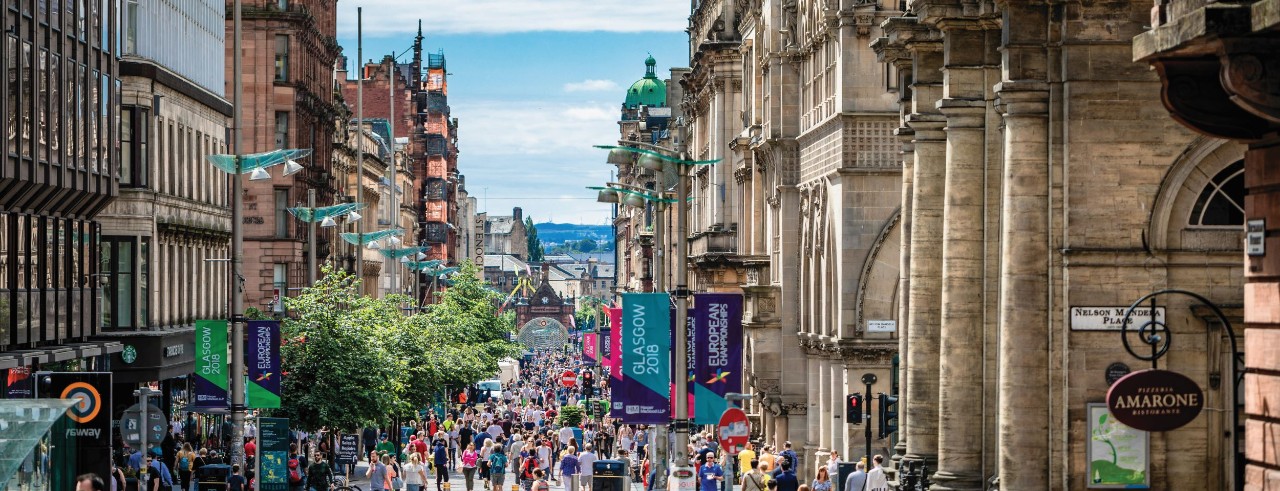 People walk on a busy, lively street in Glasgow, Scotland. 