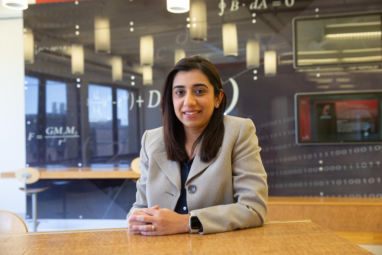 Sumra Bari sits at a desk with a decorative equation behind her.