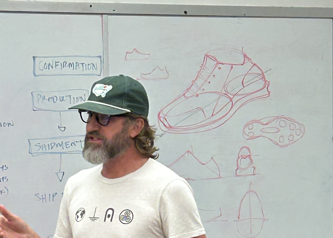 Charley Hudak in front of a whiteboard with a tennis shoe design on it 