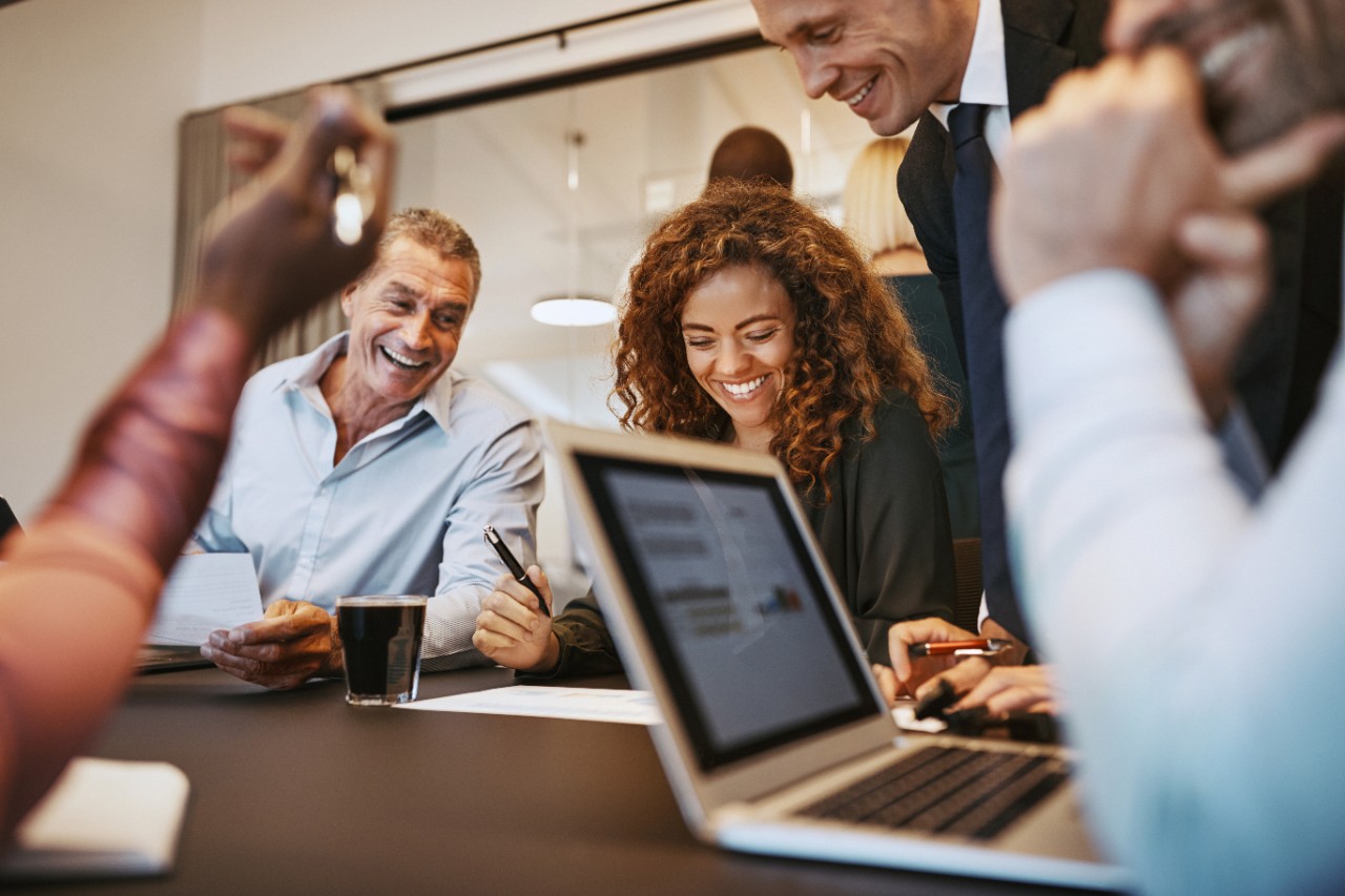 A group of people in business clothes gather around a table.