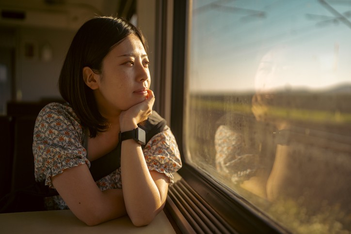 A woman stares out of a window in a train car