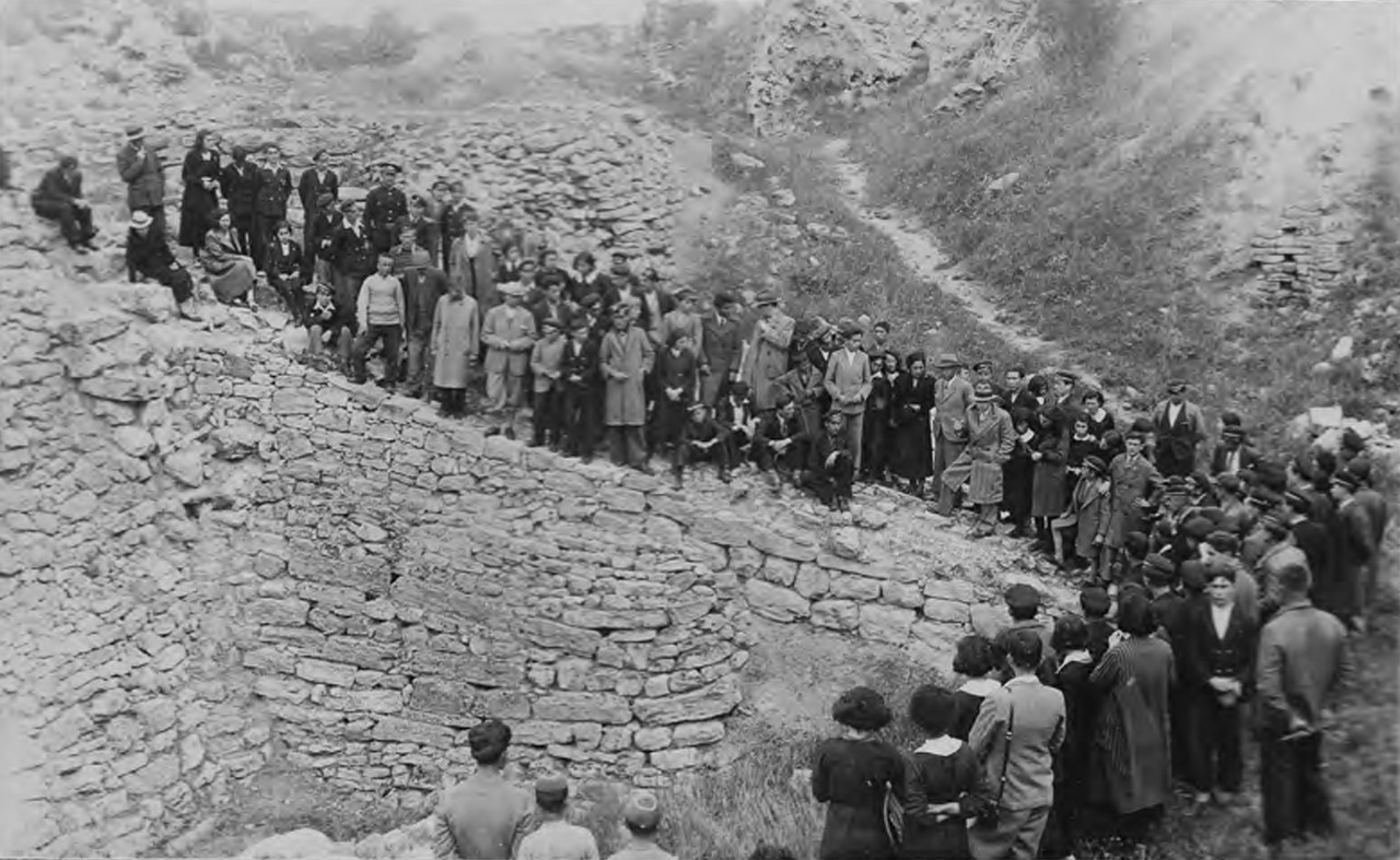 A crowd gathers along the ruins of a wall to listen to a lecture on Troy.