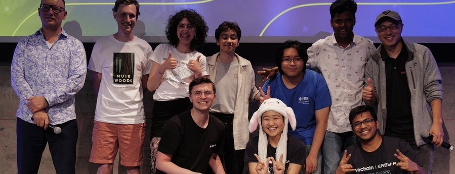 A group of people smile on stage after winning a hackathon.