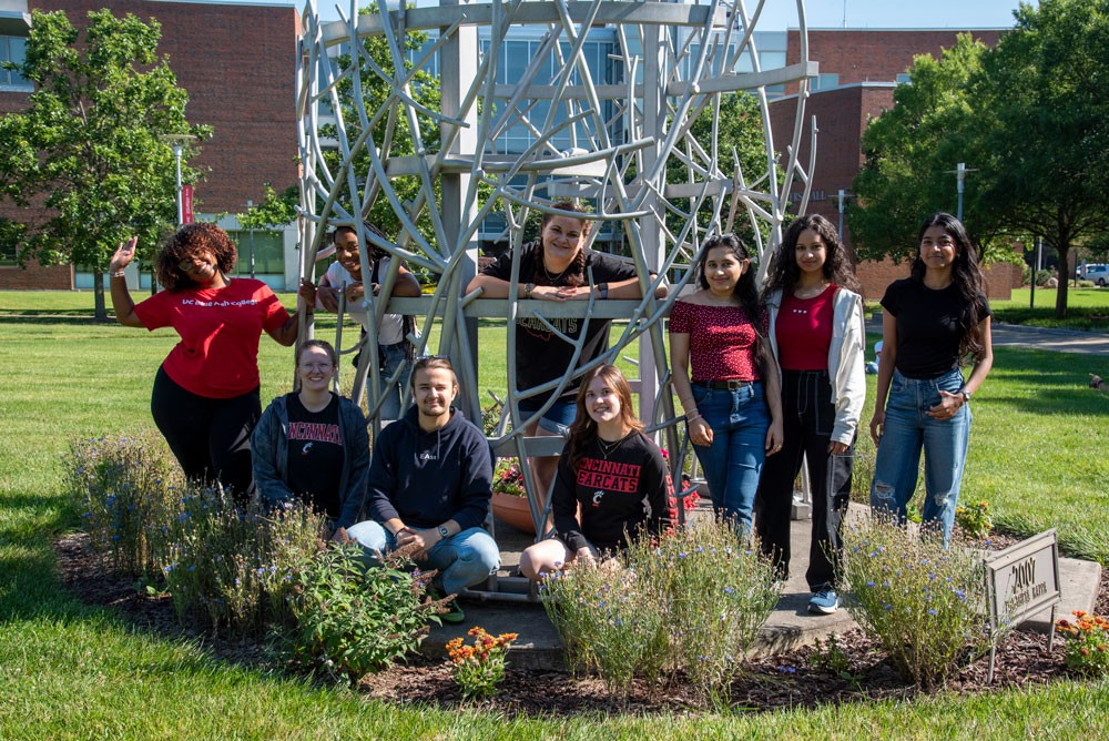 Student group posing by sculpture on UC Blue Ash College outdoor campus