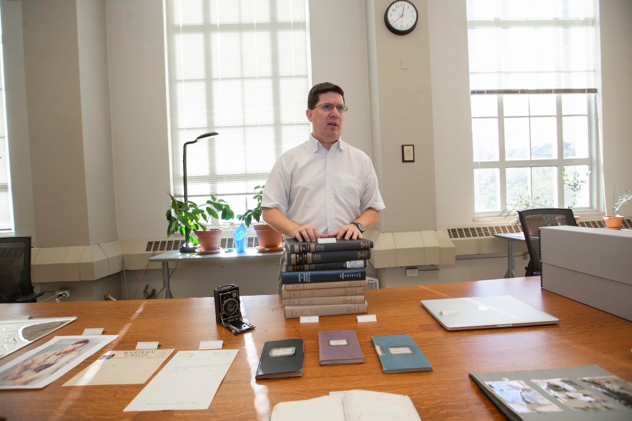 UC Classics researcher Jeff Kramer stands in front of photos, journals and documents from UC's Troy excavation in the 1930s.