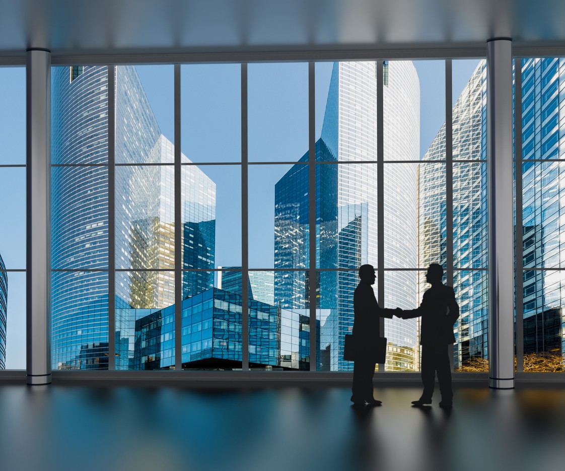 Businessmen shaking hands inside business tower