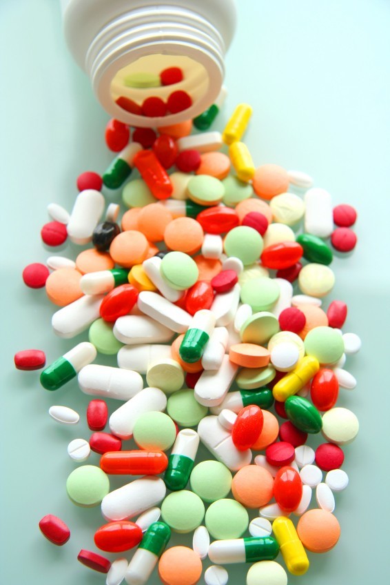 Pills of different colors spilling out of bottle