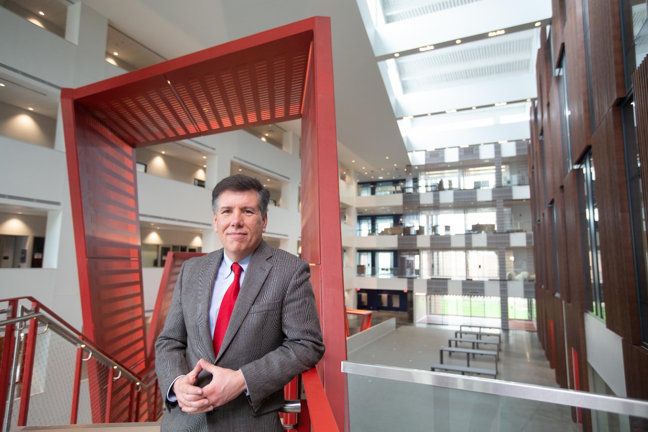 UC Professor David Niven poses in front of a decorative arch in Clifton Court Hall.