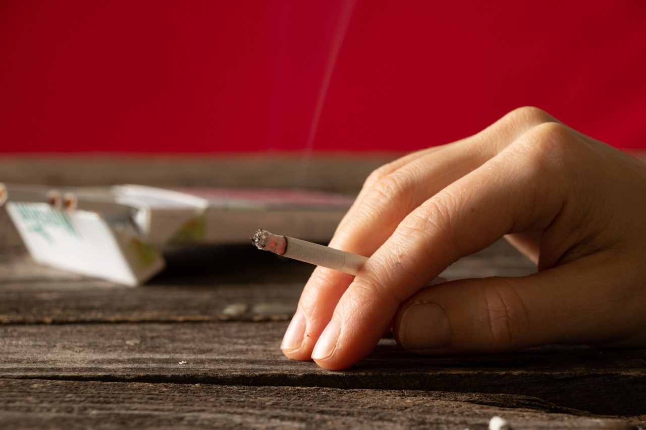 Hand holding a cigarette on a table