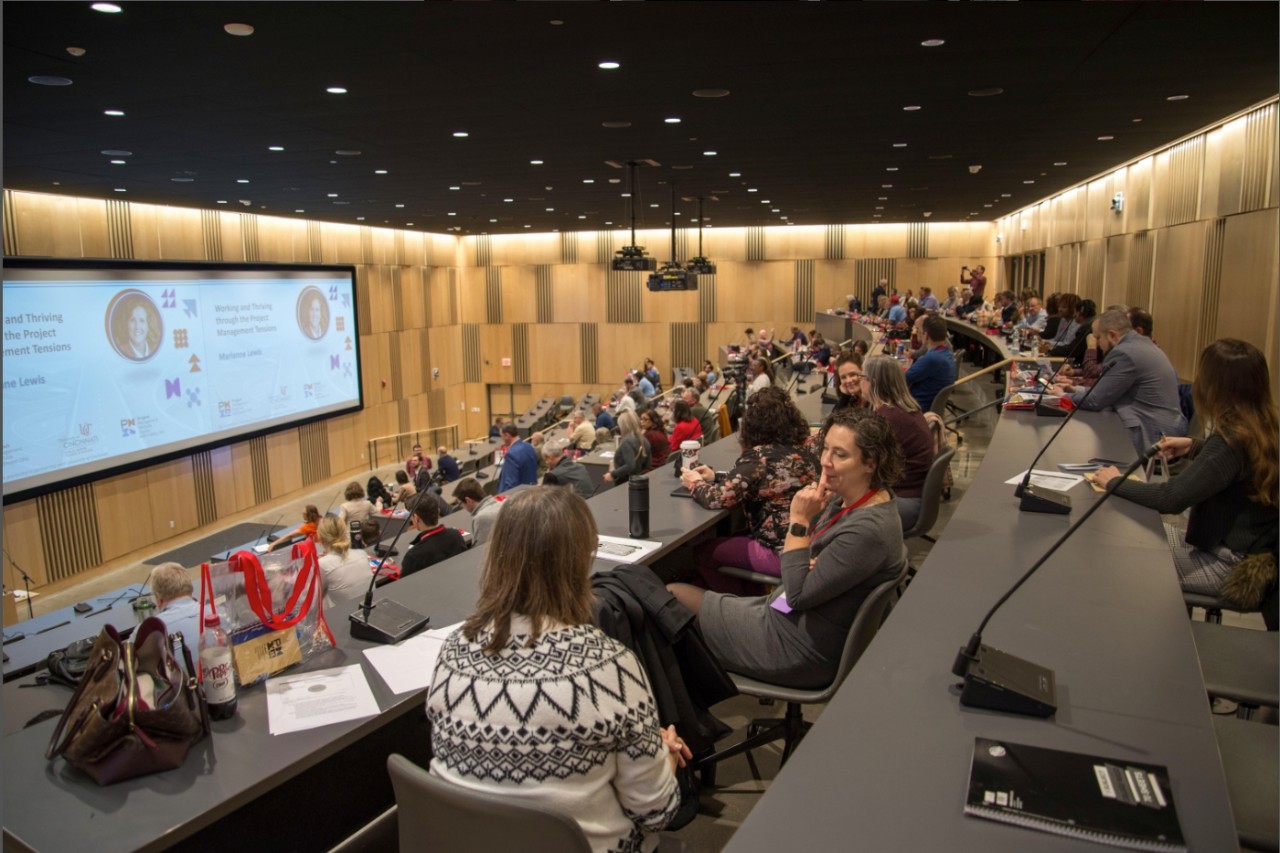 Conference attendees sit in staggered rows in Lindner Hall Room 1410 auditorium