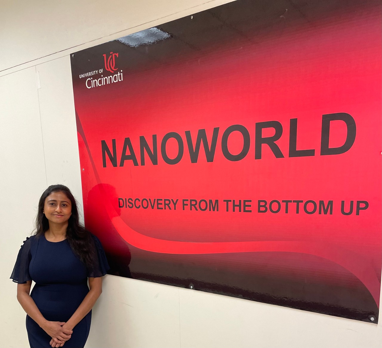 A woman stands in front of a red sign on the wall that says "Nanoworld" 