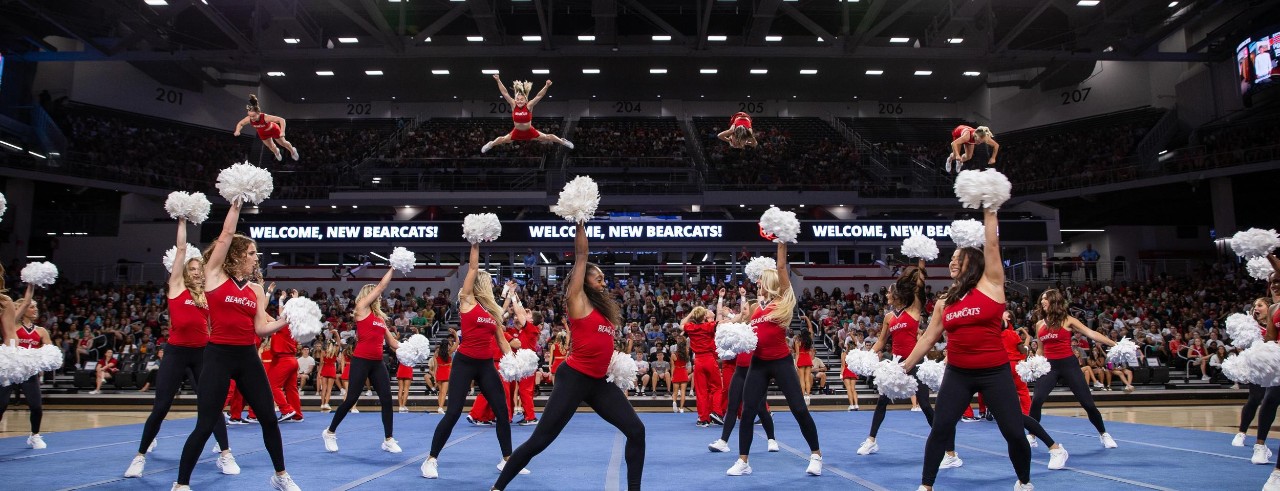 UC Cheer Team with pom poms dances for first-year students in Fifth Third Arena