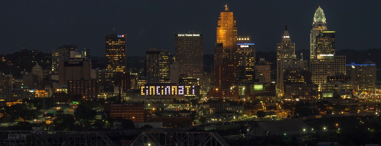 Duke Energy Cincinnati Sign, with city surroundings, in downtown Cincinnati at night.