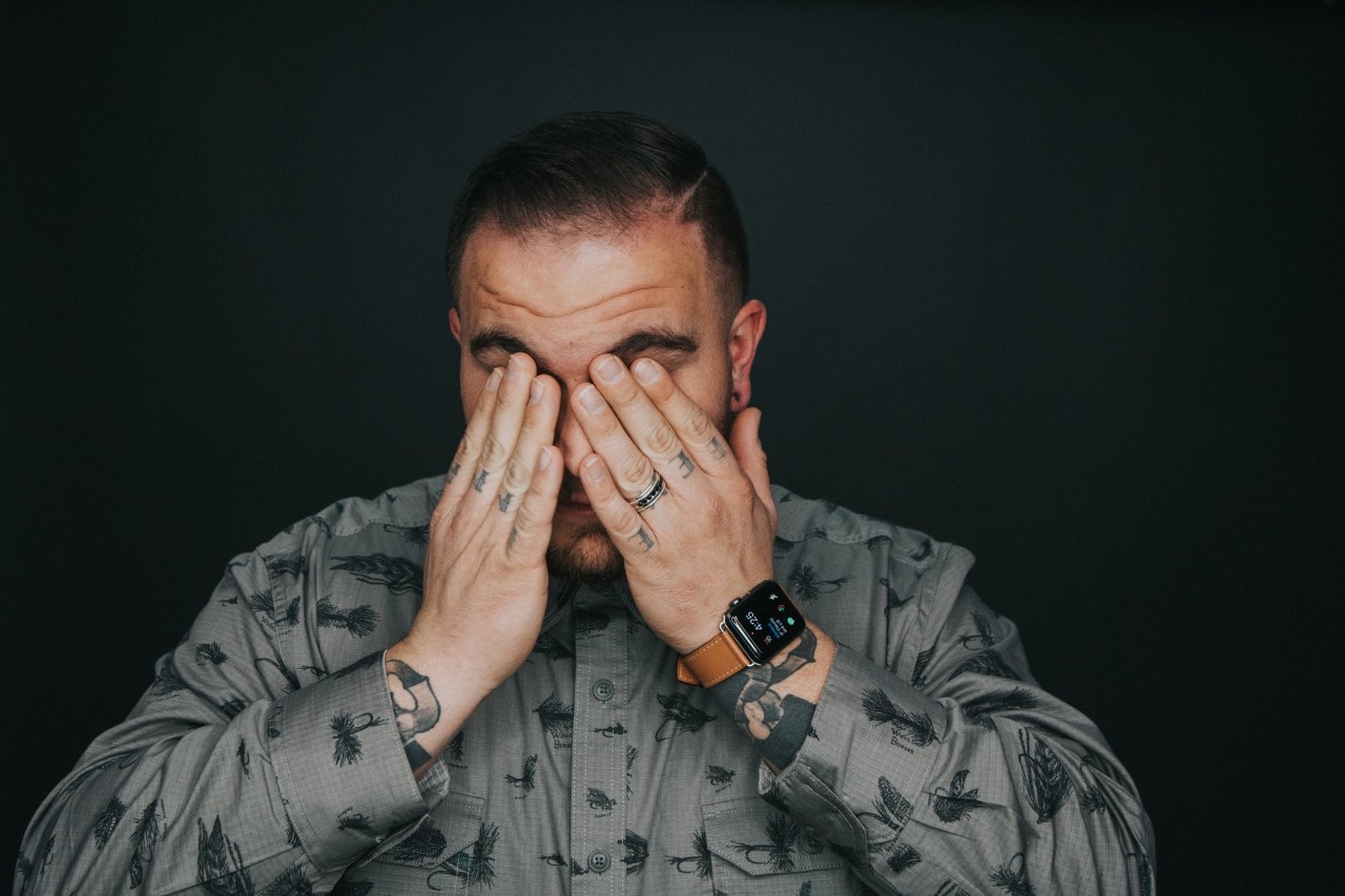 A man puts his hands over his face while in pain