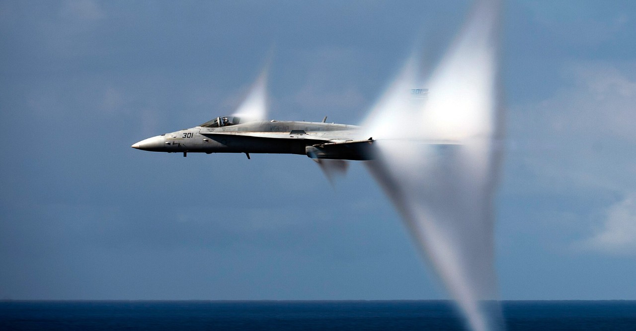 A vapor cone forms around a fighter plane approaching the speed of sound.