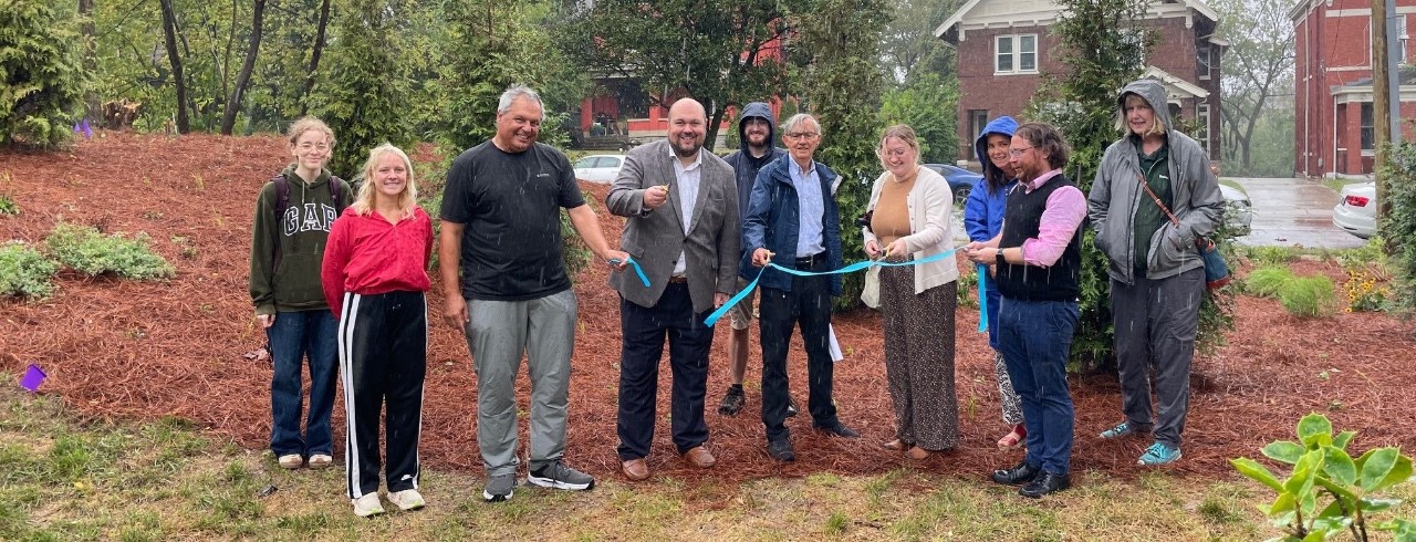 A group of people host a ceremonial ribbon cutting for the Tiny Forest.