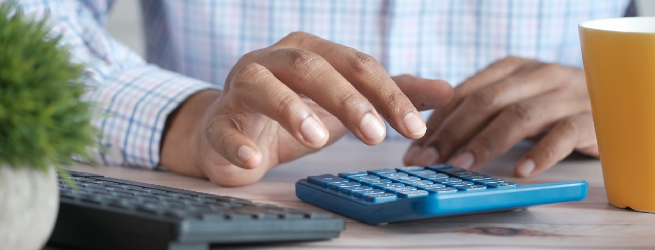 Close-up photo of a man's hands using a calculator.