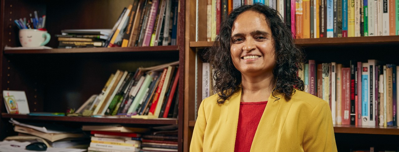 Shailaja Paik stands in front of her bookcases