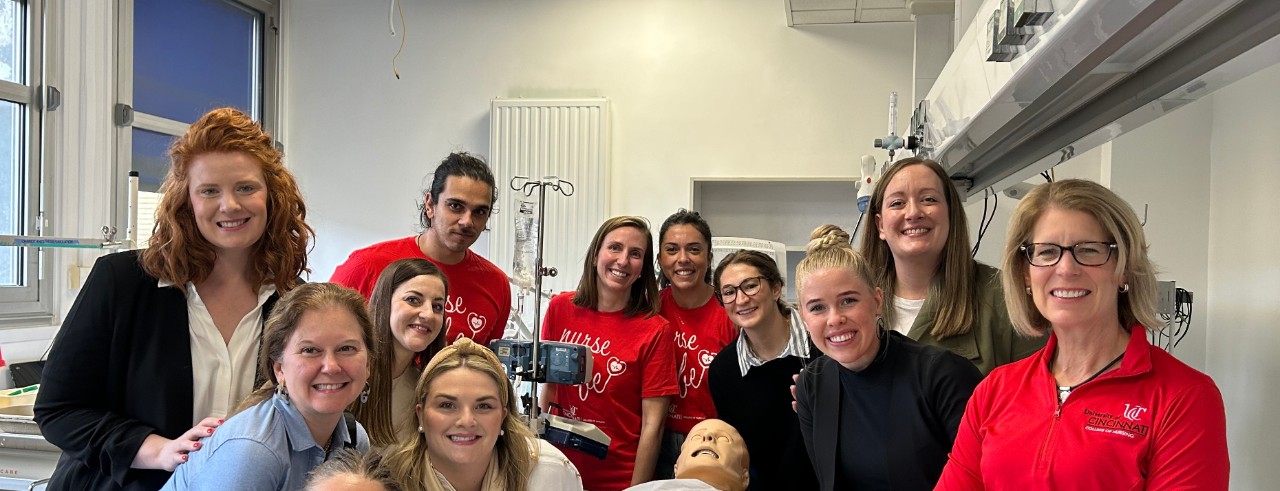 students and faculty standing with simulation manikin