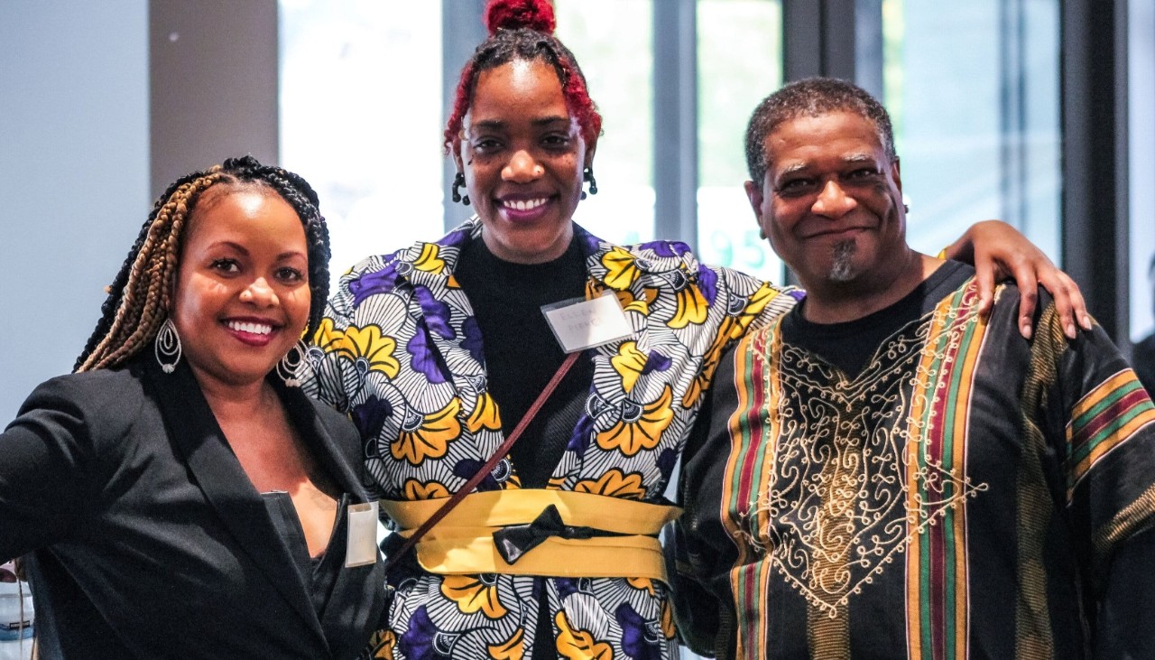 A man and a woman in African dress with a woman in a black suit.