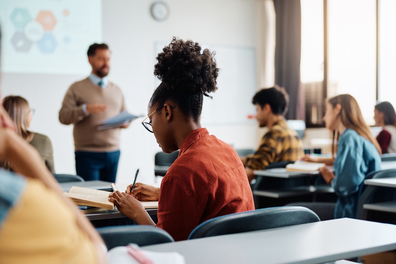 A black female student takes notes during class.