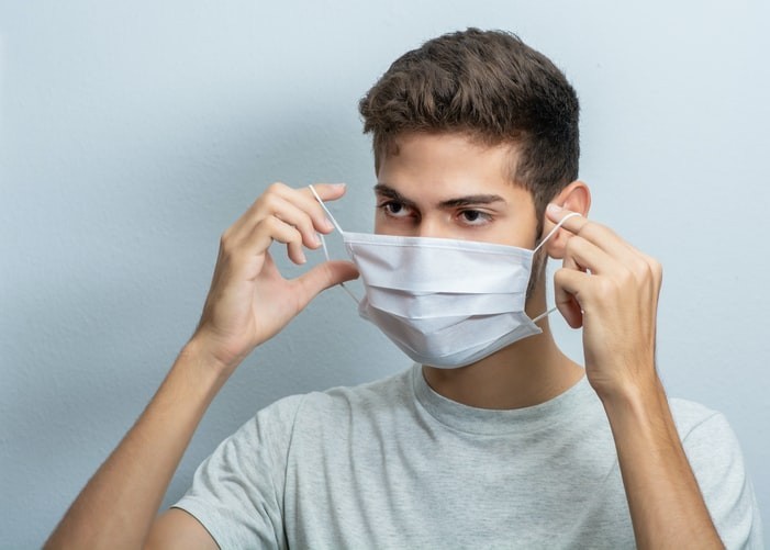 Person putting on disposable face mask.