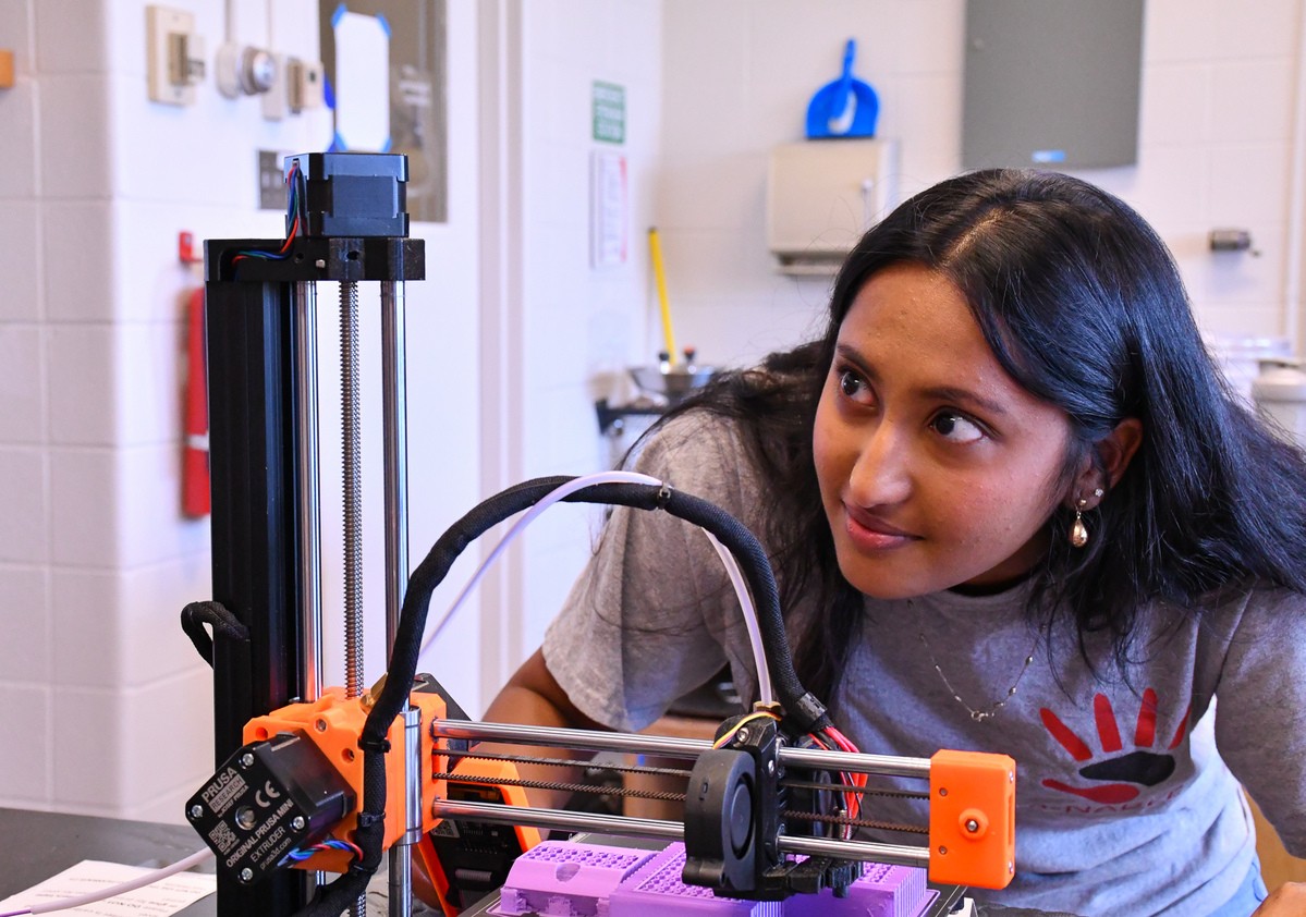 A UC student inspects a 3D printer.