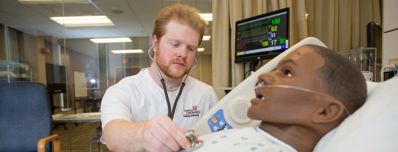 male nursing student with manikin at simulation lab