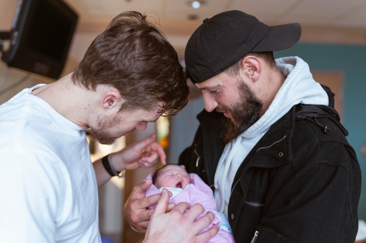 two men with newborn baby